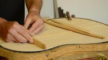 Luthier manufacturing a guitar in the workplace video