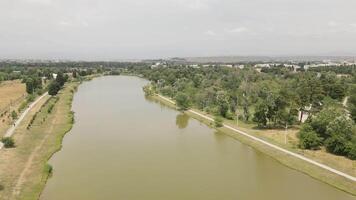 Aerial zoom in view of Rustavi Central Park featuring a calm lake surrounded by trees and walking paths, popular for recreation cycling and nature enjoyment in Georgia video
