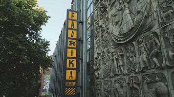 Tbilisi, Georgia, 2025 - drone Close up view of Fabrika hostel facade in Tbilisi with vibrant yellow sign and preserved Soviet artwork depicting industrial and cultural motifs video