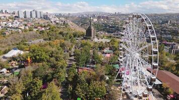 Yerevan, Armenia - 19th october, 2024 - Aerial view tourist enjoy ferris wheel ride in Victory Park with cityscape and buildings of Yerevan. Sunny autumn day carousels day out things to do concept video