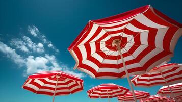 Red and white striped beach umbrellas under blue sky and clouds photo
