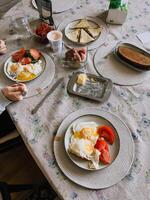 Family sharing hearty breakfast around wooden table, feasting on crispy fried eggs, ripe tomatoes, warm tortillas, yogurt, morning meal filled with warmth and connection. Healthy balanced breakfast photo
