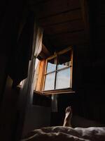 Sunlight streams through an open window in cozy wooden cabin, illuminating foot resting on bed, suggesting peaceful and relaxing morning. Sunlight casting soft glow on relaxed foot resting on bed photo