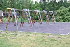 An Empty Playground Featuring Swings Amidst a Green Park Setting, Inviting Joyful Activities photo