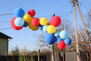 A collection of vibrant, colorful balloons is floating gracefully against a clear blue sky photo