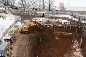 Construction of a residential building in the city, preparation of the foundation, work on an excavator. photo