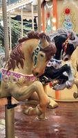 Carousel, horses, attraction for children in the city on the square on a winter evening, photo on phone