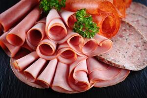 Assorted deli meats beautifully arranged on a dark serving board, ready to enjoy. photo