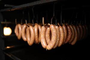 Sausages hanging inside of a smoker, ready to be cooked for a savory meal. photo