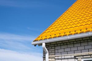 Rain Gutter Pipeline System on brick house , bright yellow metal tile roof photo