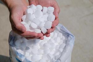 man hands holding salt for cleaning the pool photo