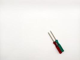 Two small colored plastic screwdrivers on a white background, red and green. copy space, flay lay, top view photo