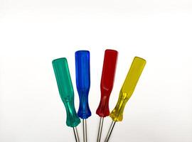 Four small colored plastic screwdrivers on a white background. copy space, flay lay, top view photo