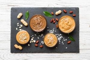 Glass jar with peanut butterin plate on table background, space for text and close up photo