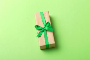 Wrapped christmas holiday handmade present in craft paper with colored ribbon. Present box, decoration of gift on table photo