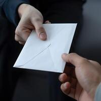 Close Up of Two People Exchanging a White Envelope in a Business Transaction Setting photo