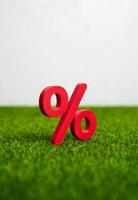Red percent figure on green grass. Concept of a ripe and ready to collect profit on the interest rate deposit. Savings growth, or favorable financial timing. photo