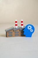 An industrial plant and a head with gears symbolizing intelligence and technology. Innovation, automation, or intellectual capital in manufacturing. photo