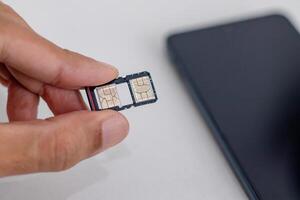 Hand holding an open SIM card slot on a smartphone photo
