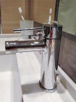 Modern chrome bathroom faucet, close-up, vertical photo