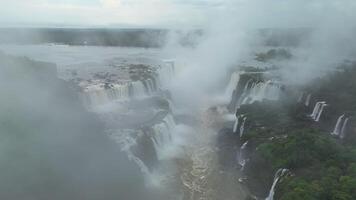 Aerial view of Iguazu Falls stretching along border with mist and rainforest video