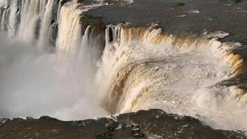 Slow motion water plunges into vast Iguazu Falls basin framed by dense forest video