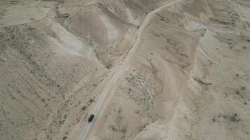Vehicle on winding desert road at Cape Ugra Uzbekistan with rugged hills view video