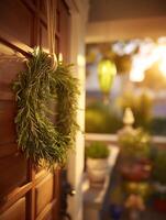 Rosemary Wreath Hanging on a Wooden Door at Sunset. A close up image of a fragrant rosemary wreath hanging on a warm brown wooden door, with a blurred background of a sunlit porch and greenery. photo
