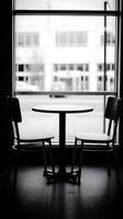 Black and White Photo of Empty Chairs and Table by Window.