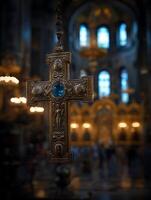 Ornate Religious Cross Hanging in a Church Interior. A detailed close up of an intricately designed golden cross with a blue gemstone, set against a softly blurred background of a church's interior. photo