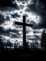 Tall Wooden Cross Silhouetted Against a Dramatic Cloudy Sky. photo
