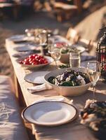 Outdoor Dinner Party Table Setting at Sunset. A close up view of a beautifully arranged table with fresh salads and other dishes, perfect for summer or spring gatherings. photo