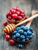 Close up of blueberries and cranberries in copper bowls with honey dipper. photo
