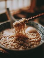 Close up of Chopsticks Lifting Noodles from a Bowl of Ramen Soup. photo