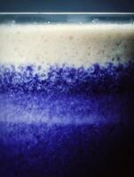 Close up of a layered beverage with creamy top and deep blue bottom. A textured image ideal for backgrounds or food and drink publications. photo