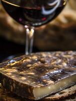 Close up of artisan cheese with red wine in background. photo
