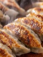 Close up of steaming, golden brown gyoza dumplings on a wooden surface. photo