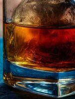 Close up of amber liquid in a rocks glass with ice. The rich colors and textures are highlighted. photo