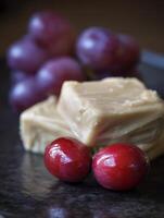 Close Up of Creamy Fudge Squares with Red Cranberries and Grapes. photo