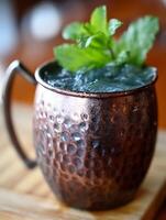 Close up of a refreshing iced drink in a copper mug garnished with mint. photo