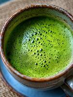 Close up of Frothy Matcha Green Tea in a Rustic Mug. photo