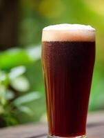 A Refreshing Glass of Dark Beer Outdoors. Enjoy the crisp, cold beverage against a lush green backdrop. photo
