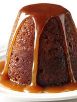 Close up of a sticky toffee pudding with caramel sauce drizzled over it. photo