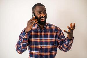 Frustrated African American man with beard shouting while holding mobile phone, showing signs of overwork and emotional strain. photo