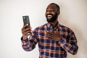 Cheerful adult black male in casual clothes chatting online, expressing joy and satisfaction during a call. photo