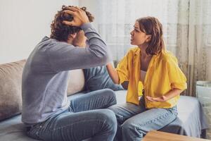 Husband and wife sitting in their apartment, trying to explain their feelings but struggling to connect. photo