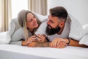 Young husband and wife relaxing and flirting in bed, enjoying a peaceful morning full of love and positive emotions. photo