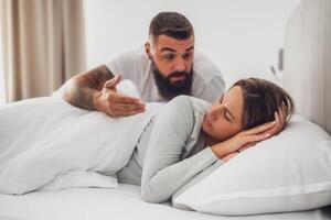 A husband and wife face each other with displeased expressions during an intense discussion, capturing the strain of misunderstanding in a marriage. photo