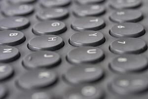 Close up of black round keyboard keys with alphabet and numerals. photo
