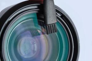 Close up of camera lens with cleaning brush on transparent surface with reflection. photo